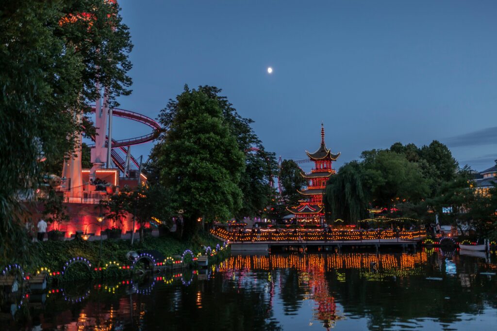 Beautiful night scene of Tivoli Gardens with Pagoda and colorful lights reflected in the lake.